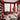CharmyDecor red and pink living room with burgundy paneled walls, a blush sofa and chair, red leather accent chair, white sculptural coffee tables, built-in shelves, and large city-view windows.