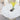 Round white table with a vase of yellow flowers and a glass of red wine on a light-colored floor.