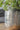 Silver textured vase with green foliage on a wooden surface