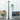 Outdoor setting with a lamp post, wicker chair, and wooden bench against a white wooden panel background.