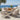 charmydecor teak wood patio dining table with six wicker chairs and white cushions overlooking ocean