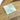 Square metallic object on a wooden surface
