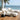 Two modern white outdoor chaise lounges with cream cushions on a coastal patio by charmydecor