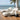 Two white acacia wood outdoor chaise lounges with cream cushions on an oceanfront deck by charmydecor