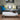 Gray sofa with plaid pillows and a white coffee table with wine glasses and bottles in a living room.