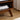 Close-up of the angled solid wood leg and lower open shelf, showing construction quality