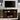 Espresso farmhouse TV stand placed under wall-mounted TV, styled with candles and flowers.