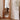 Full-length wood mirror reflecting modern wood chairs and bright window