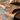 Layered jute rug on wooden table with decorative cushions and plant