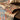 Layered jute rug on wooden table with decorative cushions and plant
