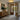Image of an illuminated entryway featuring a mounted ice glass flush ceiling light, a minimalist entry cabinet, and abstract wall art in black, gold, and brown tones.