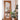 Modern organic shaped mirror leaning against wall near monstera plant and floor lamp