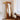 Sculptural floor mirror in corner with white curtain and wooden table reflection