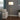 Tall tripod lamp in extended position beside a couch and curtain