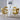 Four yellow velvet bubble back chairs around white dining table with Eiffel Tower wall art